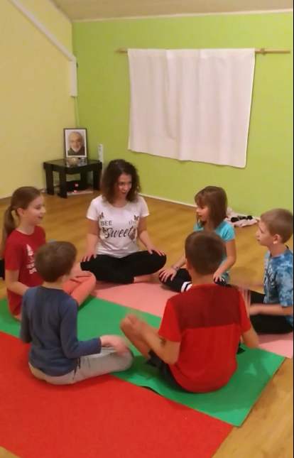 Joga Móni törökülésben ül öt gyermek körülülte szintén törökülésben